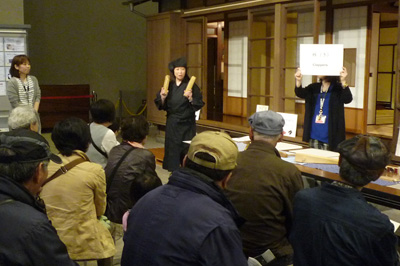 黒子姿で鳴り物を持つスタッフの画像