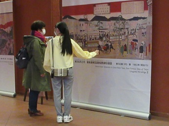 会場に飾られた明治の東京のバナーを見ながら説明をする学生